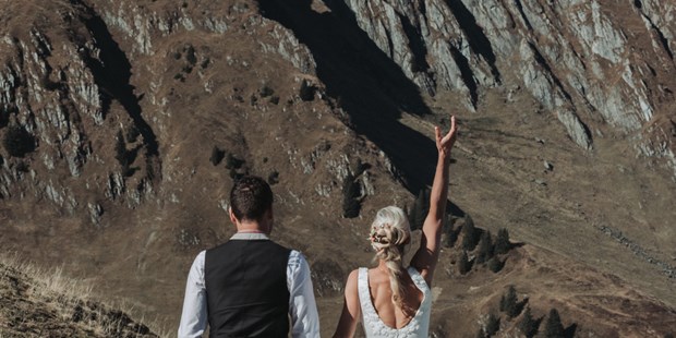 Hochzeitsfotos - Berufsfotograf - Tiroler Oberland - Braut wirft Brautstrauß in die Luft bei dem Paarshooting in den Kitzbüheler Alpen - Sophia Eerden
